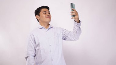 Genç Asyalı adam beyaz arka planda akıllı telefonlu bir video görüşmesi yaptı.