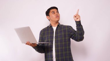 Asyalı adam dizüstü bilgisayarını tutuyor ve yan tarafı işaret ediyor.