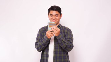 Beyaz arka plan üzerinden cep telefonu ödemelerini yapan Asyalı bir adam.