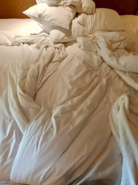 Beyaz yastıklı dağınık yatak ve yatak odası, otel ya da otel odasında yattıktan sonra battaniye.