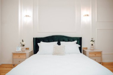 Luxury and stylish bedroom interior with king size bed, white bedding and modern light fixtures and beautiful nightstands