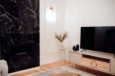 Stylish pastel apartment, Details of luxurious sofa, wooden tv table, golden light fixtures and fireplace wall