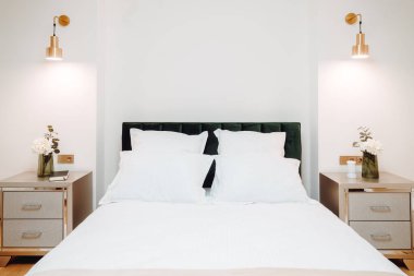 Close up of bed in master bedroom. Details of high end home design with exquisite furniture, golden light fixtures. Master bedroom design