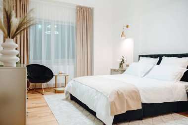 Close up of bed in master bedroom. Details of high end home design with exquisite furniture, golden light fixtures. Master bedroom design