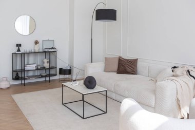 Süper beyaz, basit, temiz ve şık iç mimari modern mobilyalarla çıplak renkli ve zıt siyah elementlerle. Büyük, parlak bir oturma odasının lüks tasarımı.