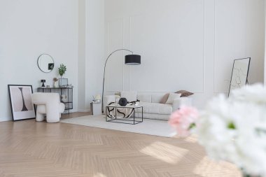 Süper beyaz, basit, temiz ve şık iç mimari modern mobilyalarla çıplak renkli ve zıt siyah elementlerle. Büyük, parlak bir oturma odasının lüks tasarımı.