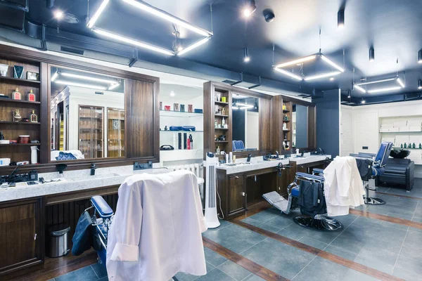 luxury barber shop interior, blue expensive furniture, wood trim, fashionable black ceiling, white robes on the backs of armchairs