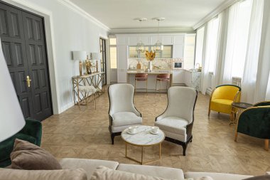 Modern bir apartman dairesi, parlak renklerde ve şık mobilyalı. Mutfak, yatak odası ve duvarsız oturma odası..