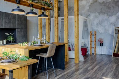 Büyük, rahat bir kır evinin içinde koyu renk bir çatı katı. Mutfak, dinlenme alanı ve yatak alanı olan açık planlı bir daire. Büyük pencereler ve ahşap dekorasyon