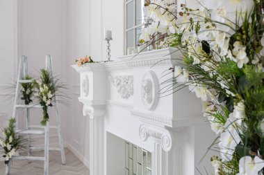 Şık mobilyaları olan lüks, ferah misafir odası kraliyet tarzında yerden tavana kocaman bir pencere yeşil bitkiler, sıva ve şömineyle süslenmiş beyaz duvarlar.