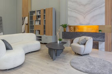 Modern stüdyo dairesinin içinde, ahşap elementli yeşil pastel renklerde lüks bir ev. Pahalı mobilyalar ve dekorasyonlar. Şöminenin yanındaki rahat oturma odası.