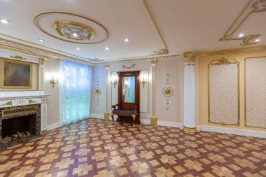 Şatafatlı bir oturma odası, duvarlarında kraliyet sarayı tarzı süslemeler olan eski ve güzel oyma mobilyalarla dolu.