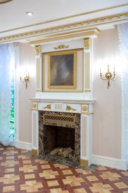 Şatafatlı bir oturma odası, duvarlarında kraliyet sarayı tarzı süslemeler olan eski ve güzel oyma mobilyalarla dolu.