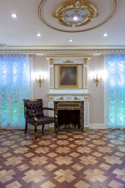 Şatafatlı bir oturma odası, duvarlarında kraliyet sarayı tarzı süslemeler olan eski ve güzel oyma mobilyalarla dolu.