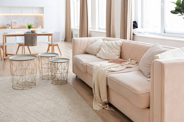 interior design spacious bright studio apartment in Scandinavian style and warm pastel white and beige colors. trendy furniture in the living area and modern details in the kitchen area.