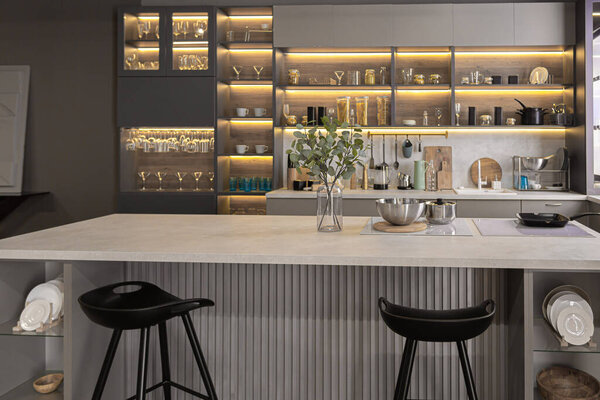 стильный роскошный интерьер кухни в ультра-современной просторной квартире в темных тонах с супер холодным освещением и островом для приготовления пищи