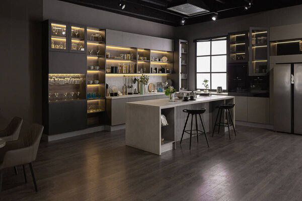стильный роскошный интерьер кухни в ультра-современной просторной квартире в темных тонах с супер холодным освещением и островом для приготовления пищи