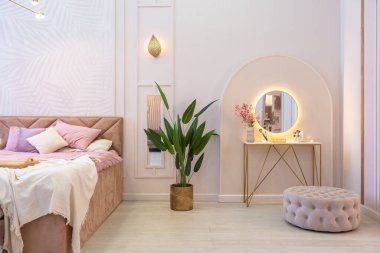 Pahalı, ferah, aydınlık, şık bir dairenin lüks, modern yatak odası. döşenmiş mobilyalar ve dekoratif ışıklandırma, yumuşak pastel renkler ve rahat atmosfer