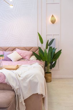Pahalı, ferah, aydınlık, şık bir dairenin lüks, modern yatak odası. döşenmiş mobilyalar ve dekoratif ışıklandırma, yumuşak pastel renkler ve rahat atmosfer