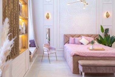 Pahalı, ferah, aydınlık, şık bir dairenin lüks, modern yatak odası. döşenmiş mobilyalar ve dekoratif ışıklandırma, yumuşak pastel renkler ve rahat atmosfer