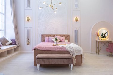 Pahalı, ferah, aydınlık, şık bir dairenin lüks, modern yatak odası. döşenmiş mobilyalar ve dekoratif ışıklandırma, yumuşak pastel renkler ve rahat atmosfer