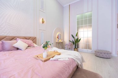 Pahalı, ferah, aydınlık, şık bir dairenin lüks, modern yatak odası. döşenmiş mobilyalar ve dekoratif ışıklandırma, yumuşak pastel renkler ve rahat atmosfer