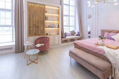 Pahalı, ferah, aydınlık, şık bir dairenin lüks, modern yatak odası. döşenmiş mobilyalar ve dekoratif ışıklandırma, yumuşak pastel renkler ve rahat atmosfer