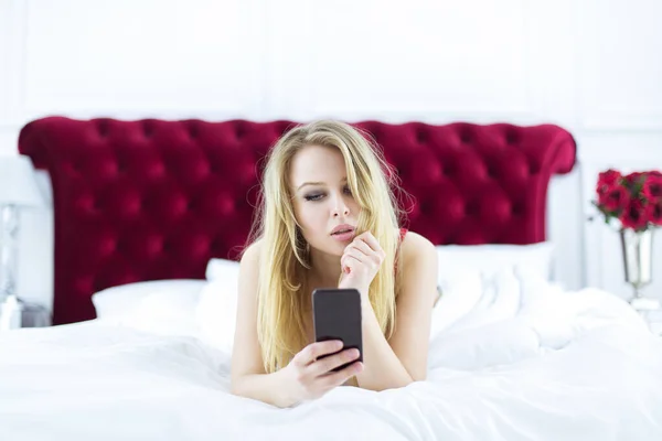 stock image Chic blonde woman in luxury white with red bedroom. Rich expensive interior.