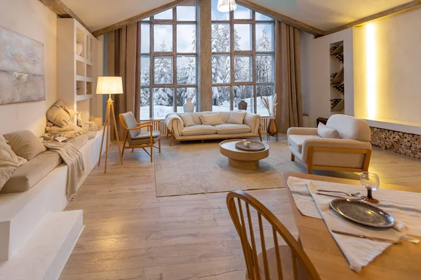 舒适温暖的家内部的别致的乡村小屋与巨大的全景窗口俯瞰着冬季的森林 开放的计划 木制装饰 温暖的色彩和家庭壁炉 — 图库照片