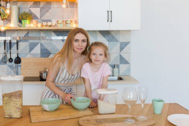 Güzel sarışın anne ve şirin küçük kız şık bir tasarımı olan şık bir dairede eğleniyor ve oynuyorlar.