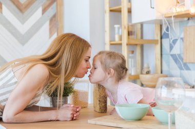 Güzel sarışın anne ve şirin küçük kız şık bir tasarımı olan şık bir dairede eğleniyor ve oynuyorlar.