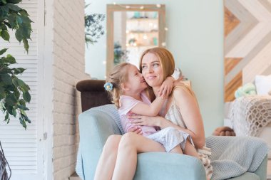 Güzel sarışın anne ve şirin küçük kız şık bir tasarımı olan şık bir dairede eğleniyor ve oynuyorlar.