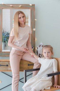 Güzel sarışın anne ve şirin küçük kız şık bir tasarımı olan şık bir dairede eğleniyor ve oynuyorlar.