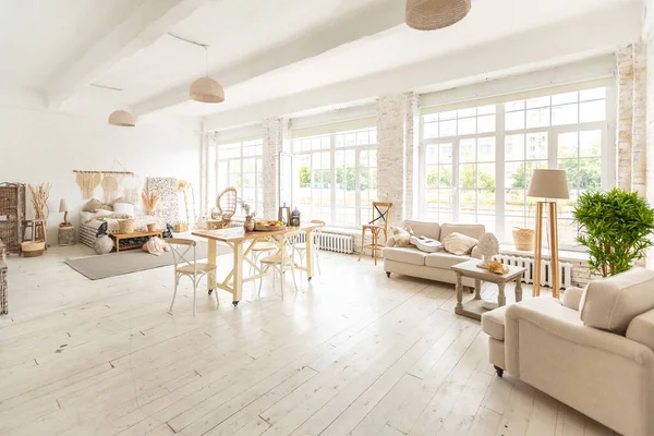 stock image Large spacious room with a trendy loft design of sitting area. huge windows and stylish wicker light furniture inside. an abundance of ethnic decor