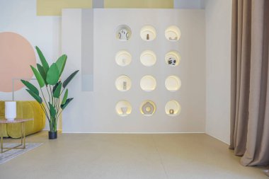 Modern açık-plan oda iç mimarisi. Pastel renklerde ve grafik duvar dekorasyonlu. Çok yüksek tavanlar ve büyük bir pencere. Altın metalik elementli yumuşak stil mobilyalar.