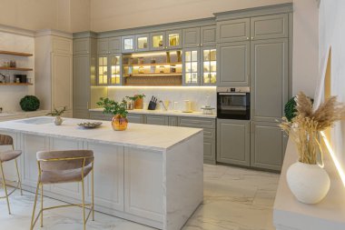Yumuşak pastel renkli rahat bir stüdyonun ultra modern zarif iç mekânındaki son moda ev trendleri. Yemek pişirmek için bir adası olan şık bir mutfağın yakın çekimleri