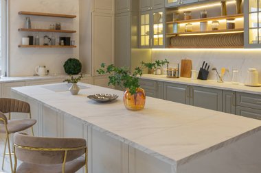Yumuşak pastel renkli rahat bir stüdyonun ultra modern zarif iç mekânındaki son moda ev trendleri. Yemek pişirmek için bir adası olan şık bir mutfağın yakın çekimleri