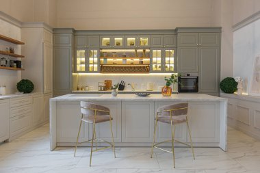 Yumuşak pastel renkli rahat bir stüdyonun ultra modern zarif iç mekânındaki son moda ev trendleri. Yemek pişirmek için bir adası olan şık bir mutfağın yakın çekimleri
