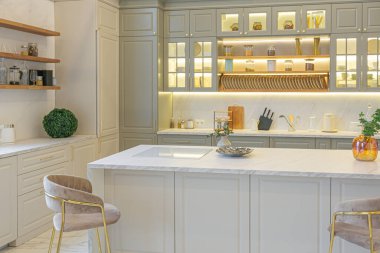 Yumuşak pastel renkli rahat bir stüdyonun ultra modern zarif iç mekânındaki son moda ev trendleri. Yemek pişirmek için bir adası olan şık bir mutfağın yakın çekimleri