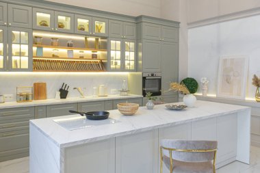 Yumuşak pastel renkli rahat bir stüdyonun ultra modern zarif iç mekânındaki son moda ev trendleri. Yemek pişirmek için bir adası olan şık bir mutfağın yakın çekimleri