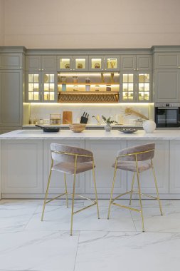 Yumuşak pastel renkli rahat bir stüdyonun ultra modern zarif iç mekânındaki son moda ev trendleri. Yemek pişirmek için bir adası olan şık bir mutfağın yakın çekimleri