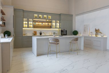 Yumuşak pastel renkli rahat bir stüdyonun ultra modern zarif iç mekânındaki son moda ev trendleri. Yemek pişirmek için bir adası olan şık bir mutfağın yakın çekimleri