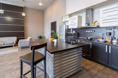 Yumuşak ve sıcak renklerde çağdaş, sıradan bir stüdyo tasarımı. Basit mobilyalar. Güneş ışığıyla aydınlık geniş bir oda. Gündüz vakti. Döşeme kahverengi zemin ve beyaz duvarlar .