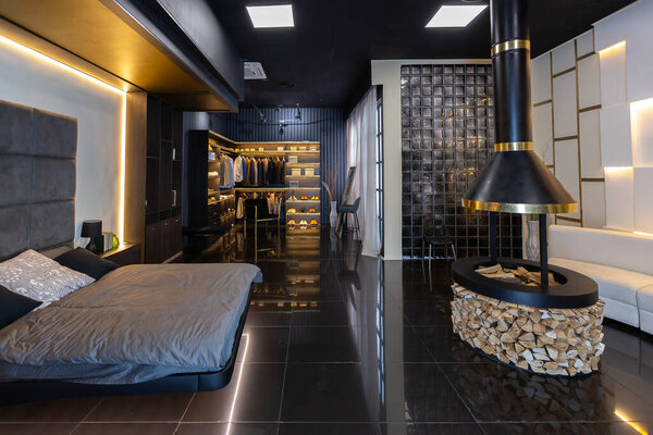 темный современный стильный мужской интерьер квартиры с освещением, декоративными стенами, камином, гардеробной и огромным окном