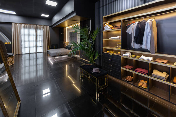 темный современный стильный мужской интерьер квартиры с освещением, декоративными стенами, камином, гардеробной и огромным окном