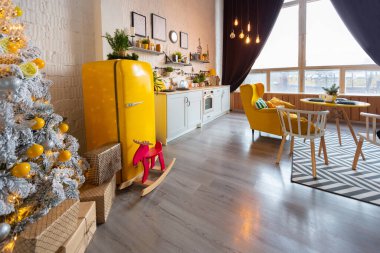 İskandinav tarzı, parlak sarı mobilyalı ve yeni yıl ışıklarıyla süslenmiş stüdyo dairesinin son moda moda iç tasarımı..