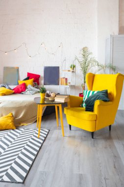 İskandinav tarzı, parlak sarı mobilyalı ve yeni yıl ışıklarıyla süslenmiş stüdyo dairesinin son moda moda iç tasarımı..