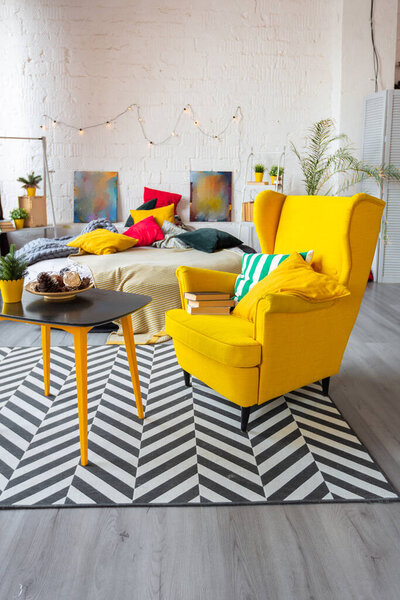 Модный модный дизайн интерьера в скандинавском стиле однокомнатной квартиры с ярко-желтой мебелью и украшенный новогодними огнями.