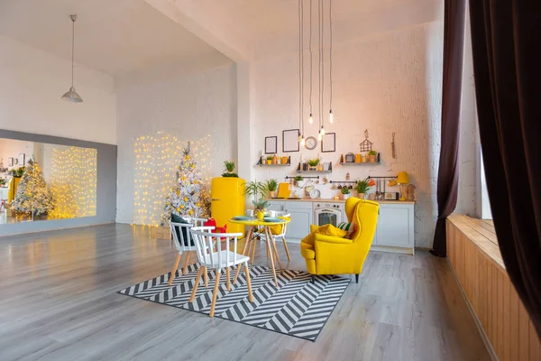 Trendy fashion luxury interior design in Scandinavian style of studio apartment with bright yellow furniture and decorated with new year lights.