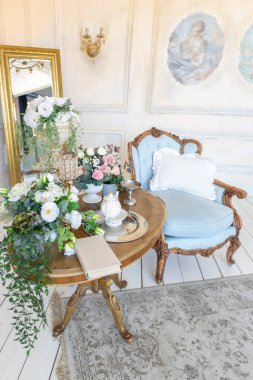 İçi bej renkli, zengin oturma odası. Barok tarzı antika pahalı mobilyalar. Duvarlar sıva ve fresklerle süslenmiş.